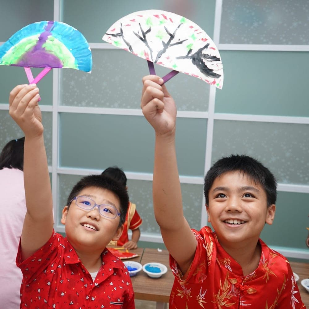Dua murid Kiddles memamerkan kipas kertas bertema Mandarin buatan mereka