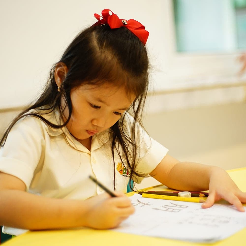 Seorang anak menulis karakter Mandarin di buku latihan
